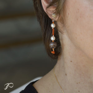 Photo portée d'une création de boucles d'oreilles en perles de culture, agate du Botswana et soie orangée