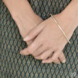 Le bracelet Arc pare la main d'une belle ligne en fil d'argent